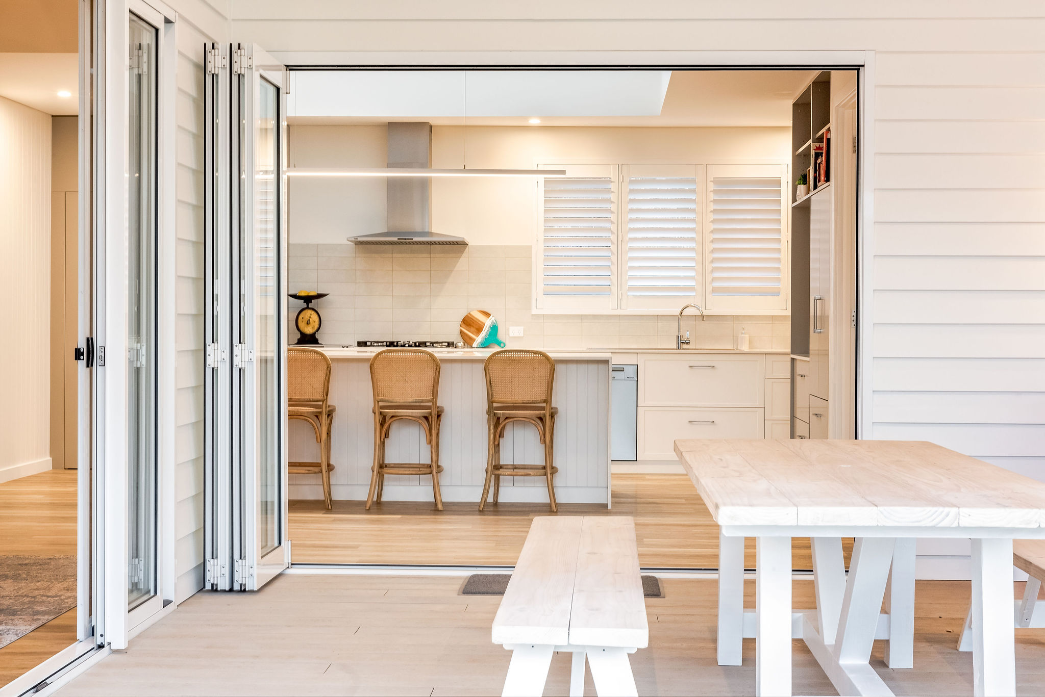 Bi-fold glass doors opening kitchen to outdoor alfresco deck