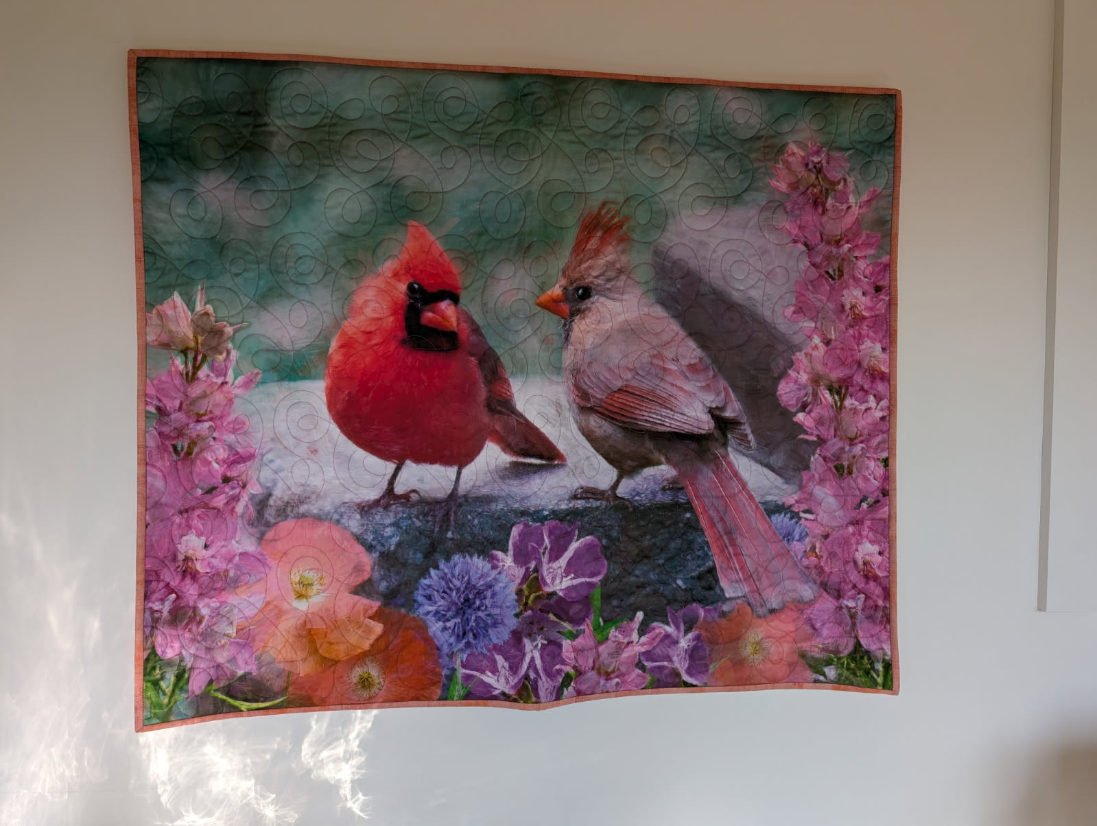 Quilted panel featuring a male and female cardinal surrounded by pink and purple flowers