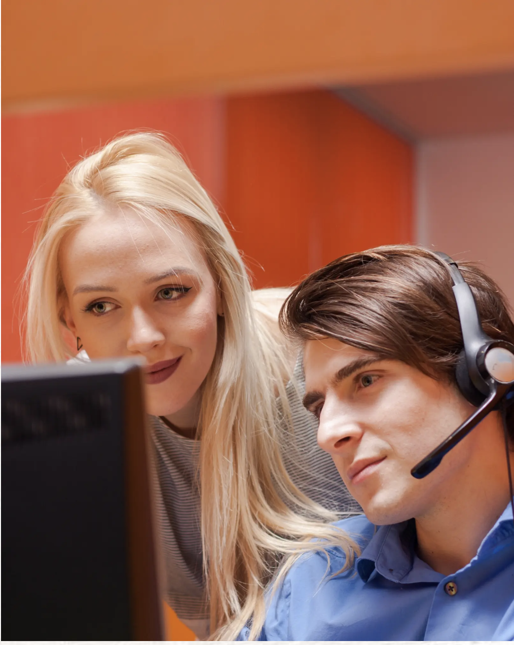Two remote agents working together at workstation with headsets