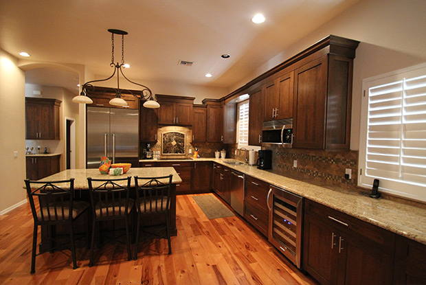 Long countertop run with built-in beverage refrigerator, wood cabinets, and plantation shutters