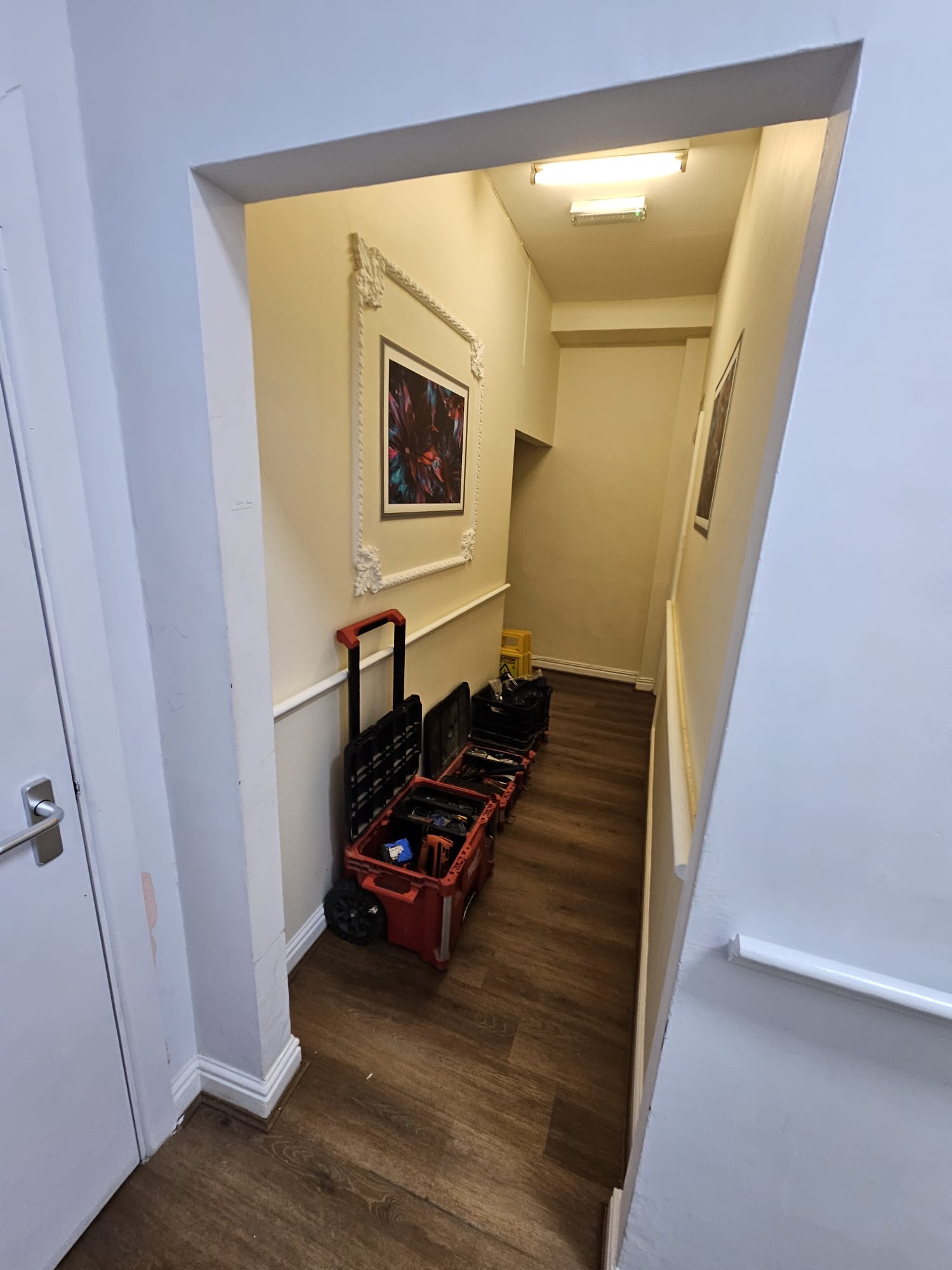 AFTER — Hallway view showing completed worksite with professional tooling staged along wall, white-painted doors, dado rail and clean site presentation