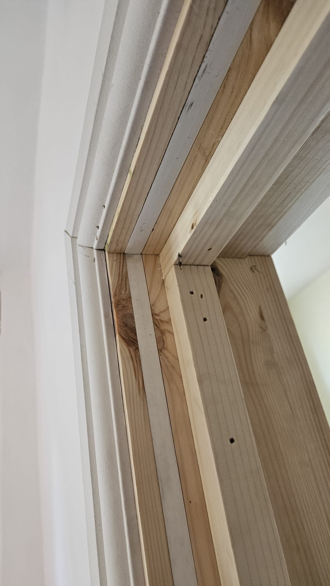 BEFORE — Exposed raw timber door frame under construction showing precision-cut joints, structural studs and unfinished architrave detailing pre-installation