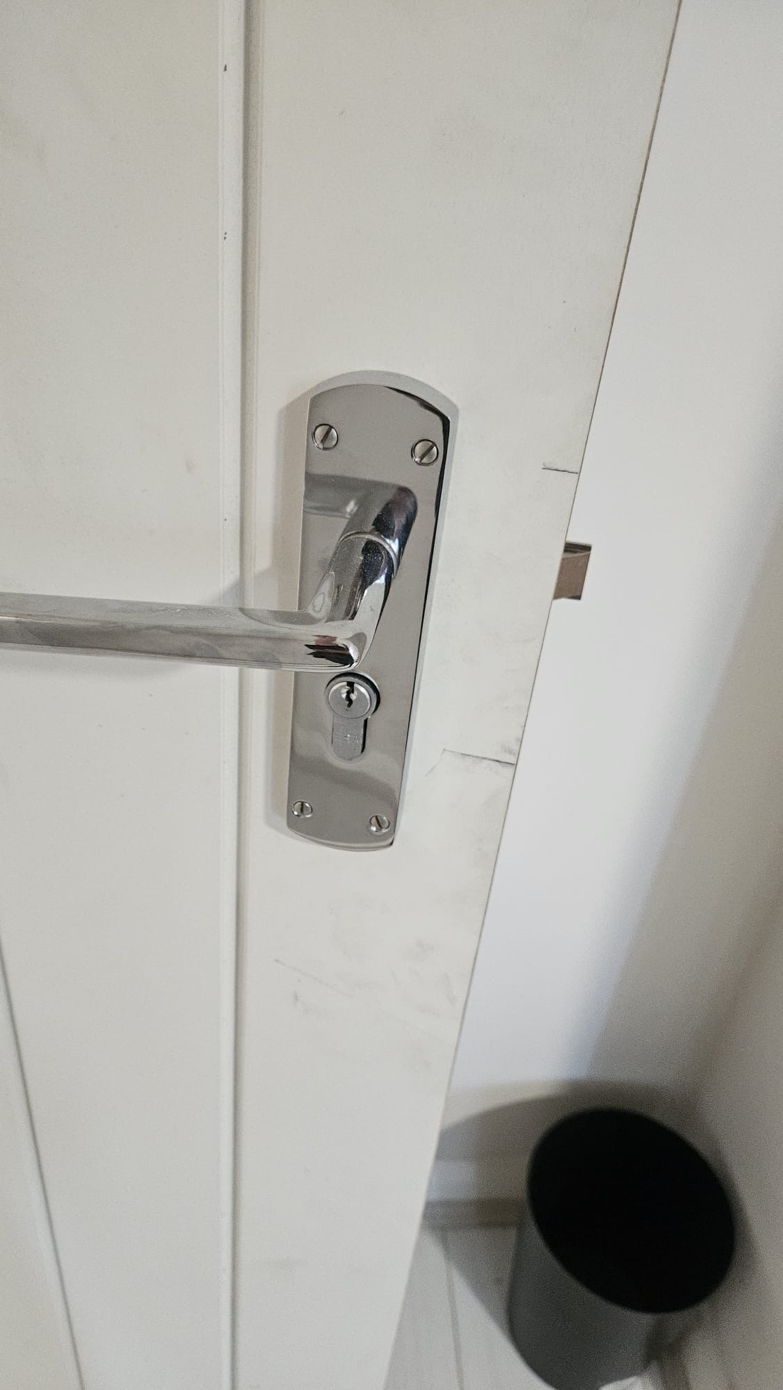 Detail of new satin chrome lever handle and escutcheon on finished white-painted fire door with intumescent seals fitted