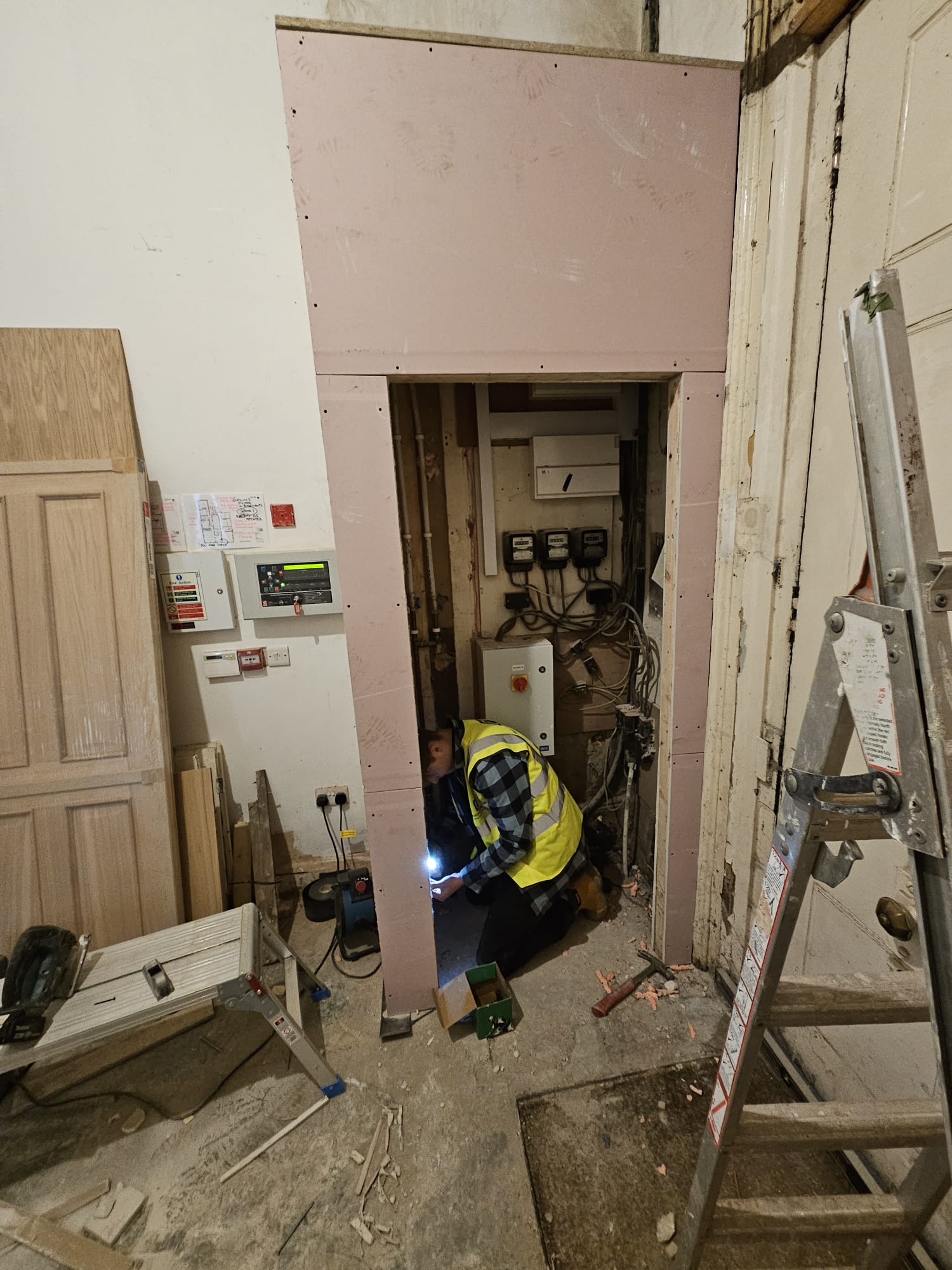 Specialist fitting fire-resistant boarding around electrical riser with precision frame construction