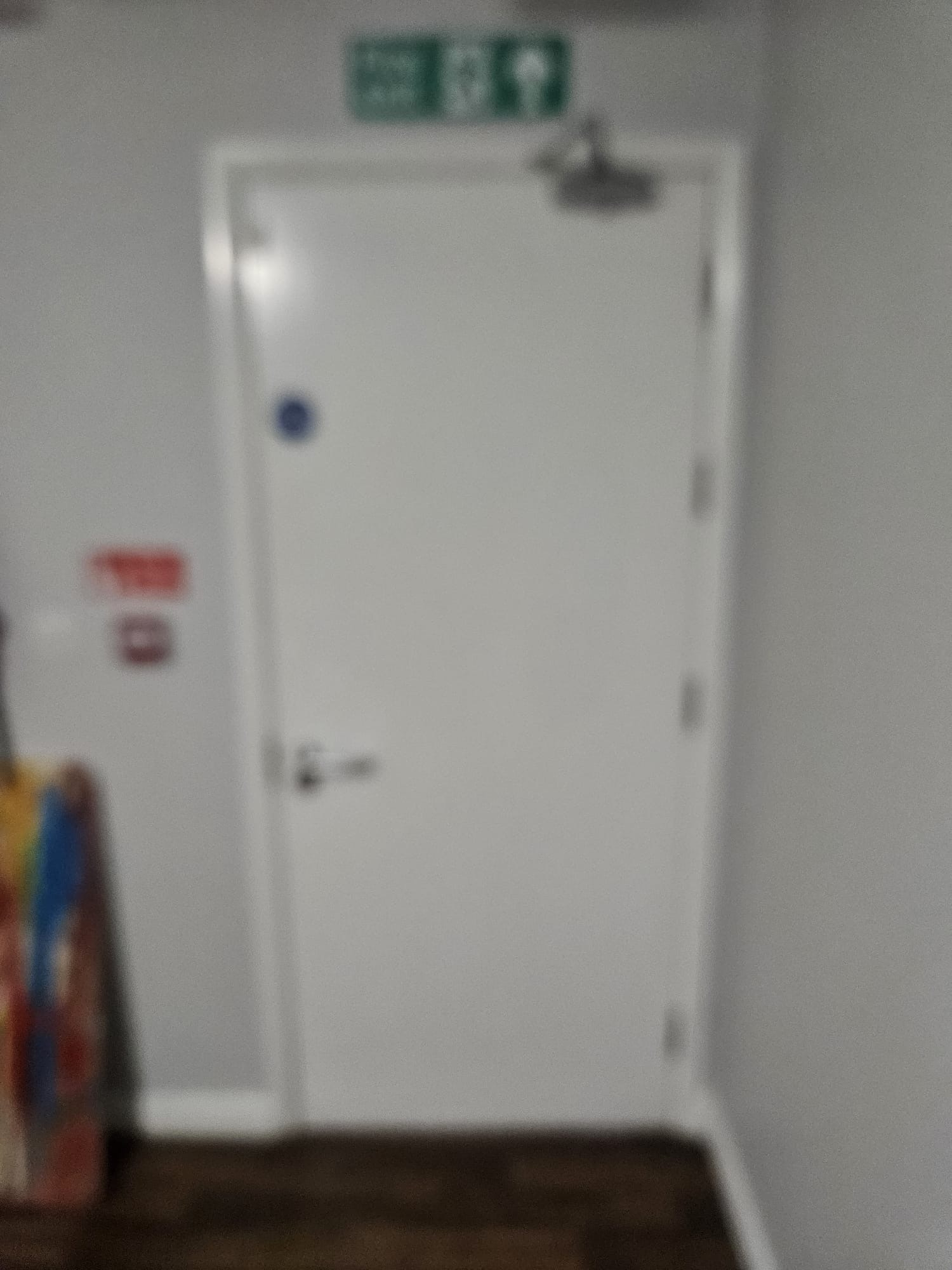 AFTER — White-painted FD30 fire door with circular blue Fire Door Keep Shut compliance sign, chrome lever handle and overhead closer in residential hallway setting