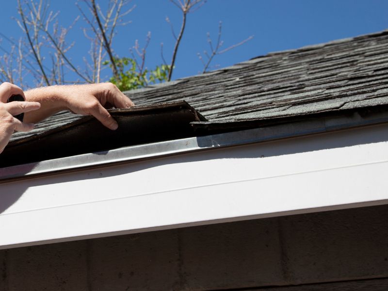 Roof shingle inspection being performed by lifting shingles to evaluate underlayment condition on an Arizona home