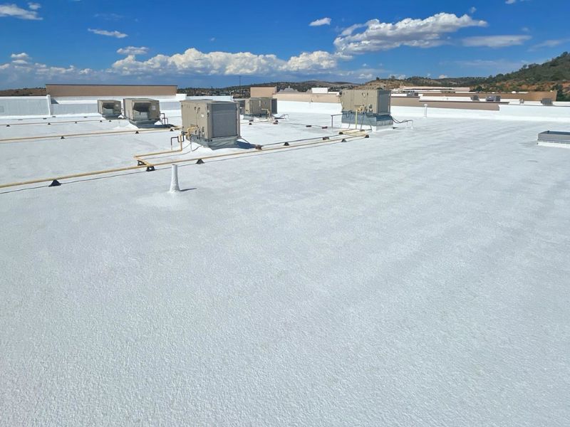 Commercial TPO flat roof installation in Northern Arizona with white reflective membrane and mountain views