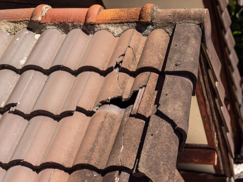 Damaged old roof tile in need of repair, showing cracked and broken concrete tiles during an Arizona roof inspection