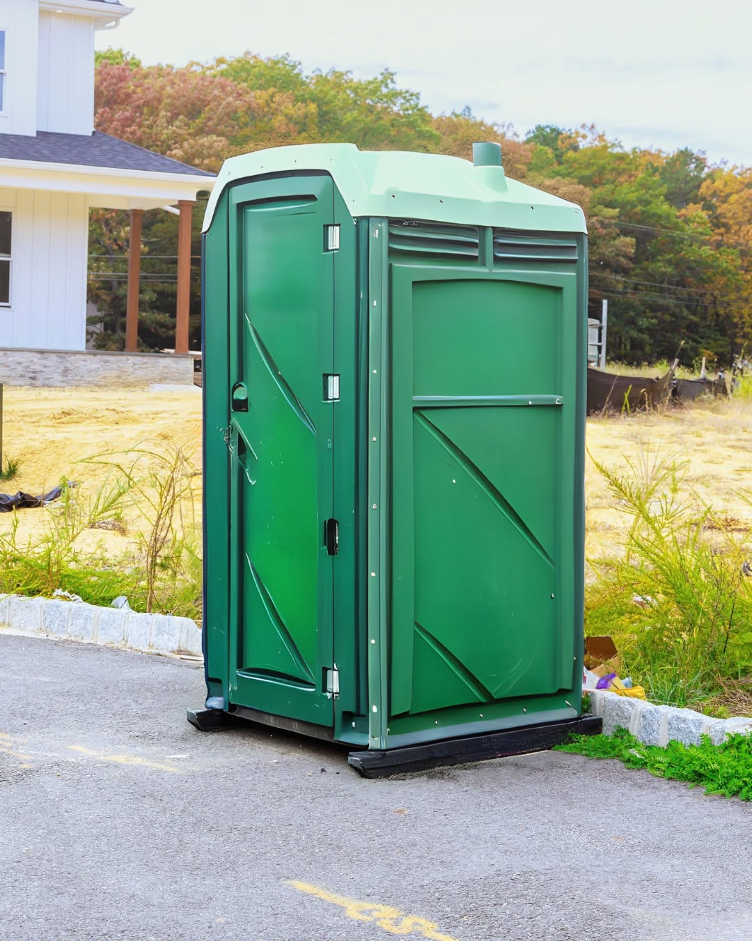 Portable toilet placed in the side yard of a home undergoing renovation