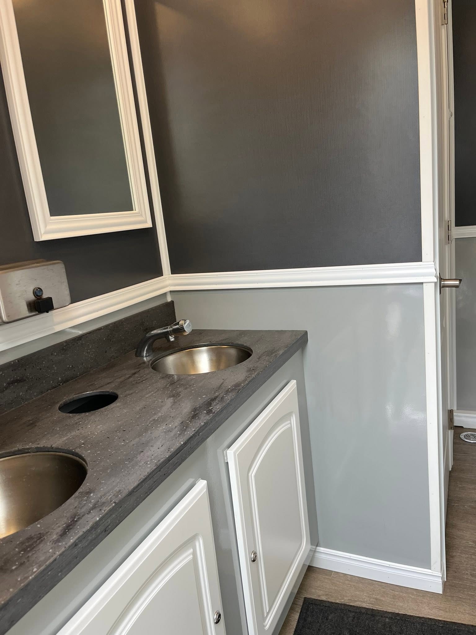 Bright interior of a portable restroom trailer with flushing toilets, running-water sinks, mirrors and vanity counters