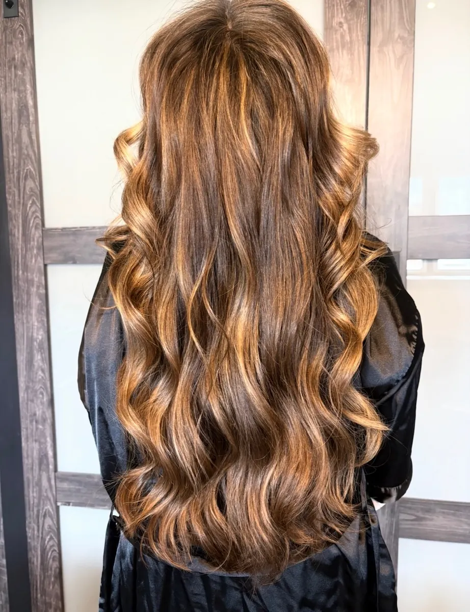 Finished long wavy caramel and brunette dimensional balayage hair extensions by Jessica Young — seamless blend, full head visible