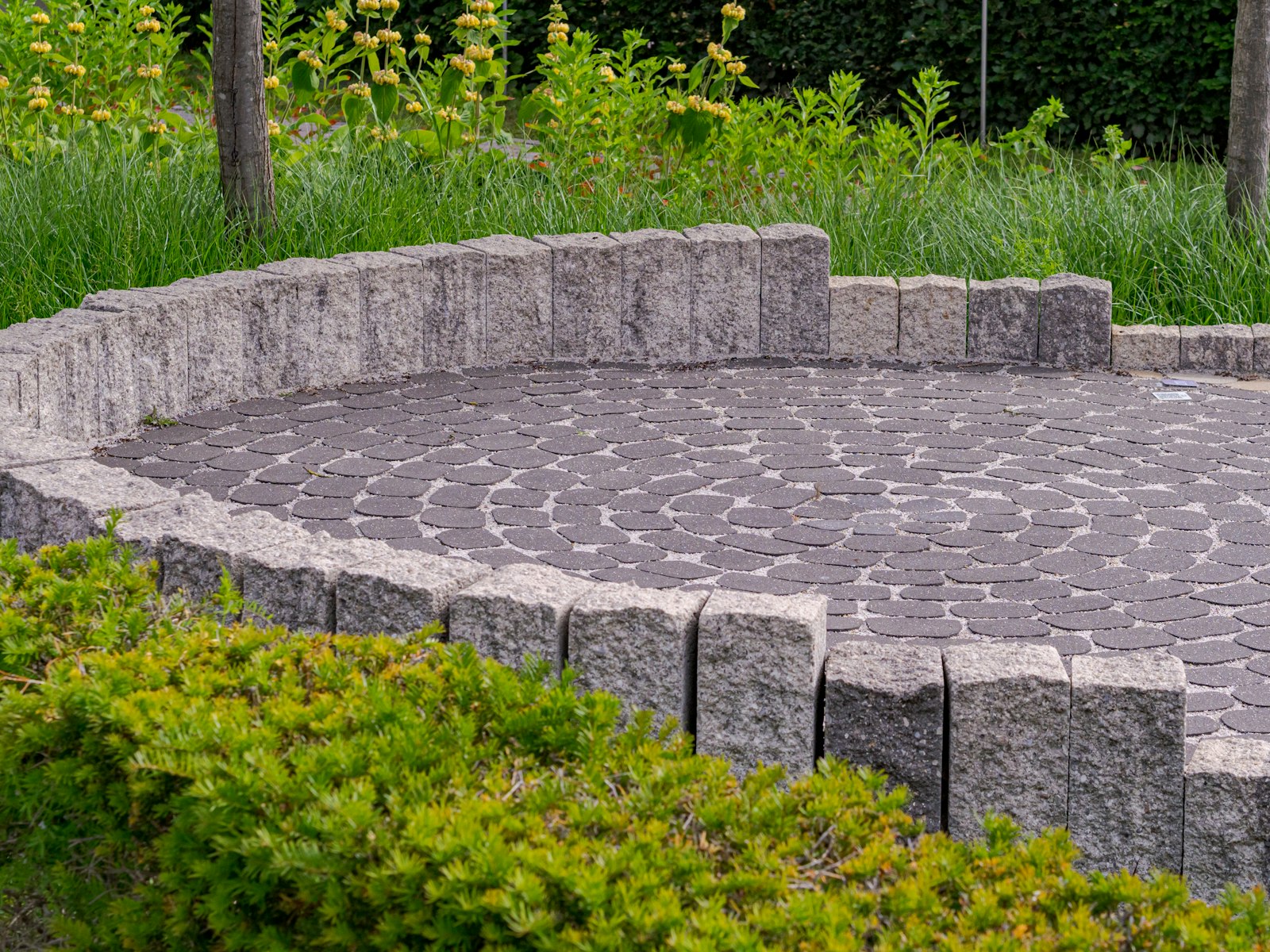 Paver patio with a low stone wall and plantings in an Arlington TX backyard