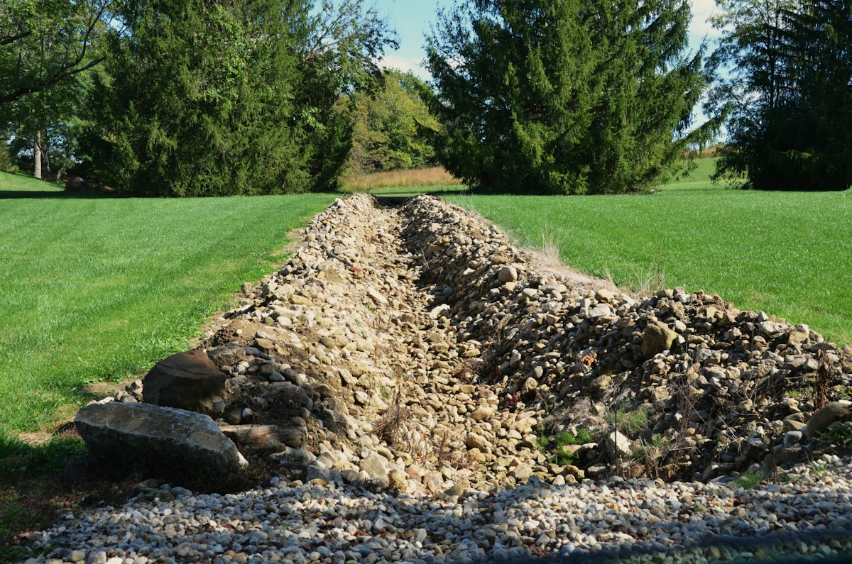 Drainage trench dug in a grassy yard with gravel and stone in Arlington TX