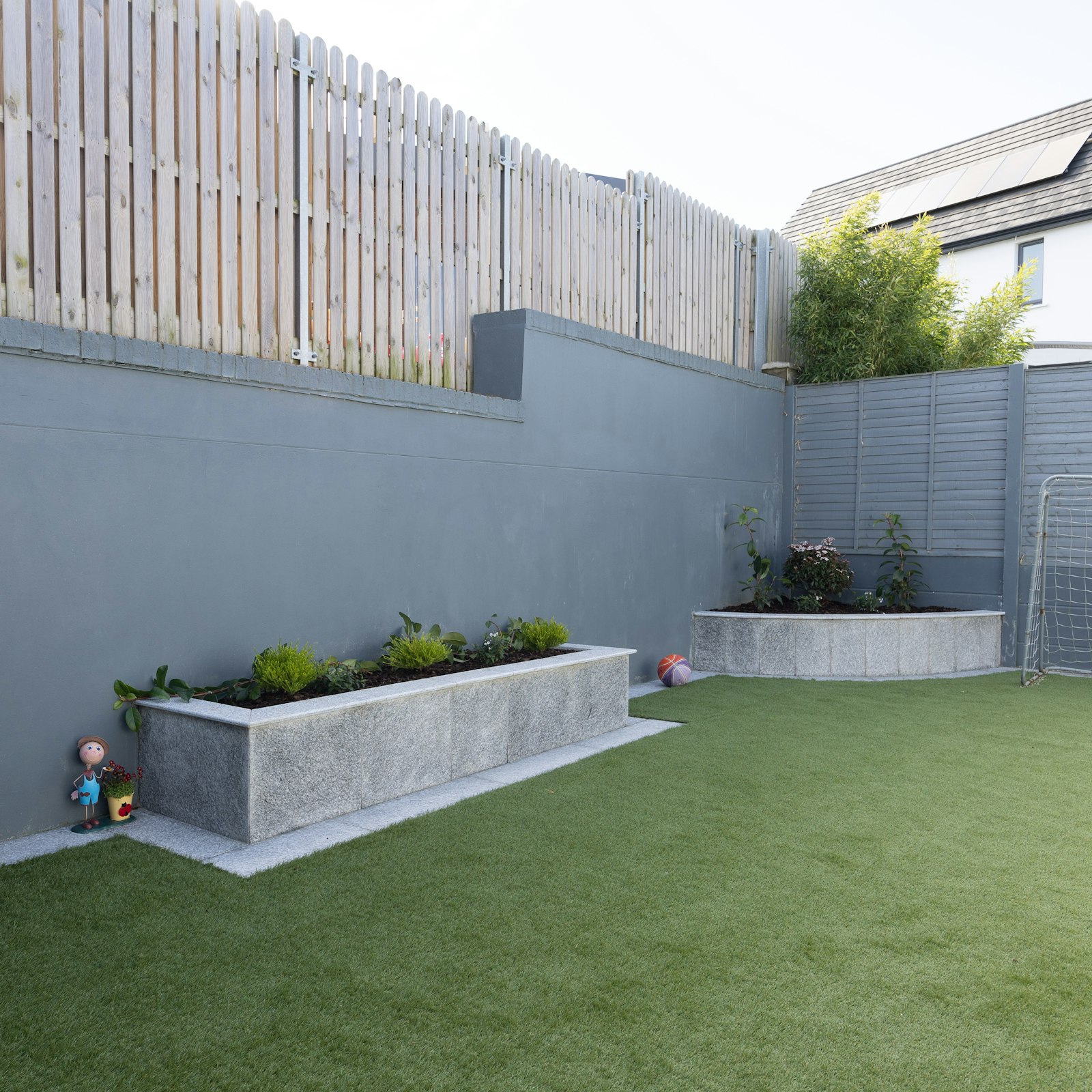 Backyard with artificial turf and a concrete planter at a home in Arlington TX