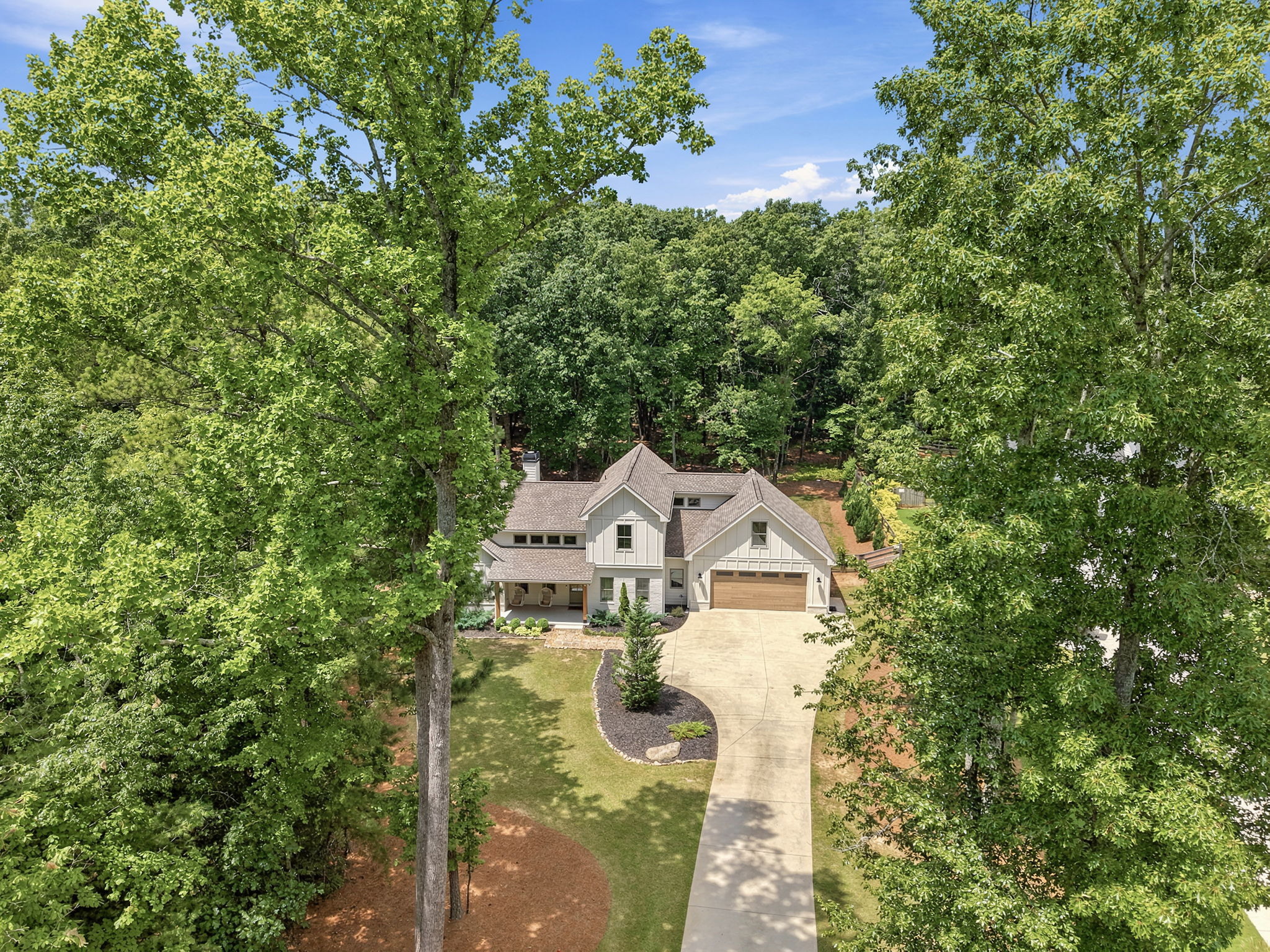 Elevated drone photo of luxury home front facade framed by mature trees showing curb appeal