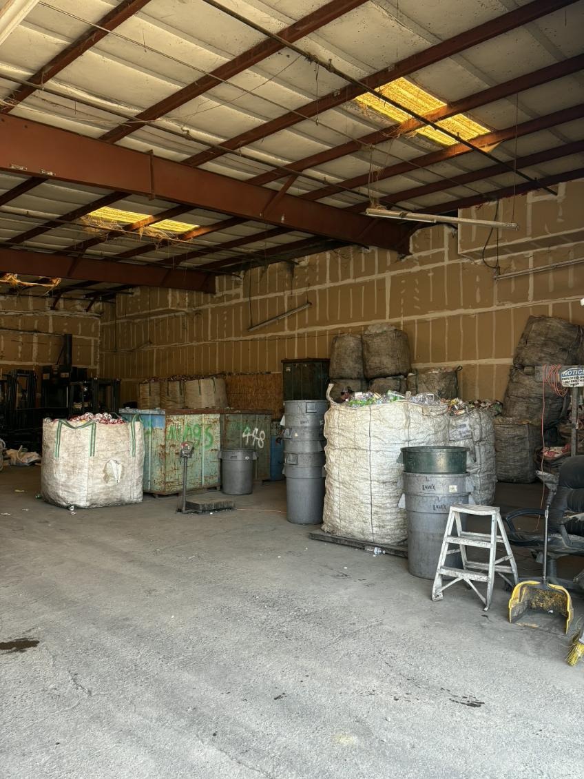 Recycling warehouse interior with large bags of CRV cans and containers near forklifts