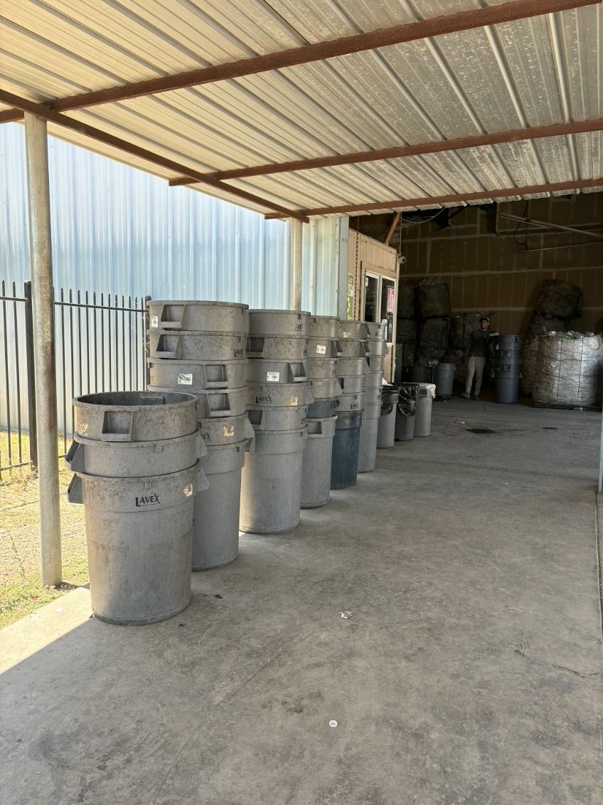 Outdoor covered area with rows of gray LAVEX bins lined up at Valdez Recycling facility entrance