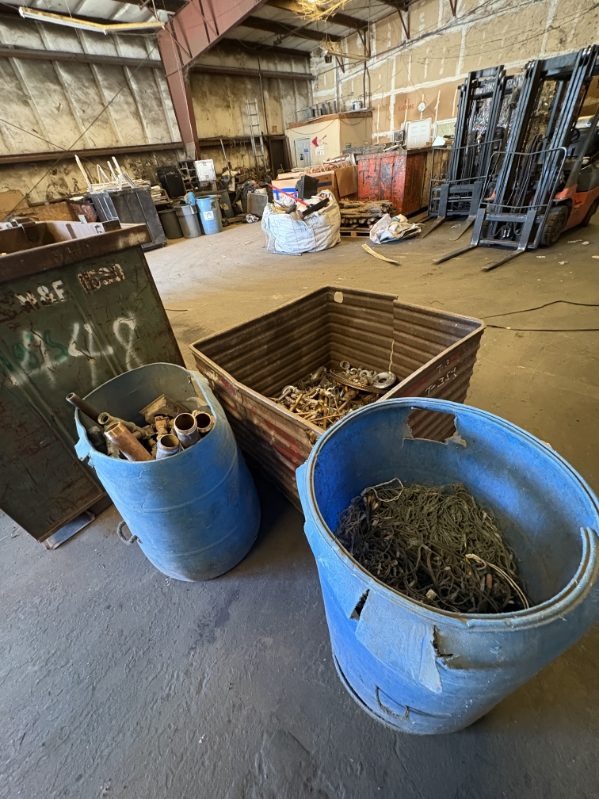 Blue barrels containing copper pipes, wires, and brass scrap metal at recycling facility