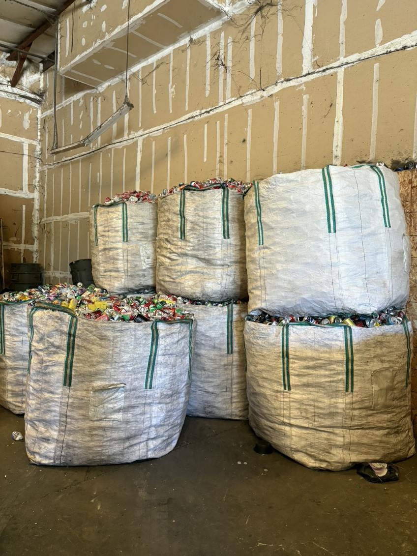 Stacks of large white bulk bags filled with aluminum cans ready for processing