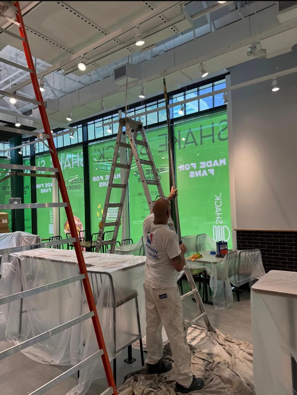 MVVAC Painting LLC team member performing professional interior commercial painting with ladder staging and surface protection