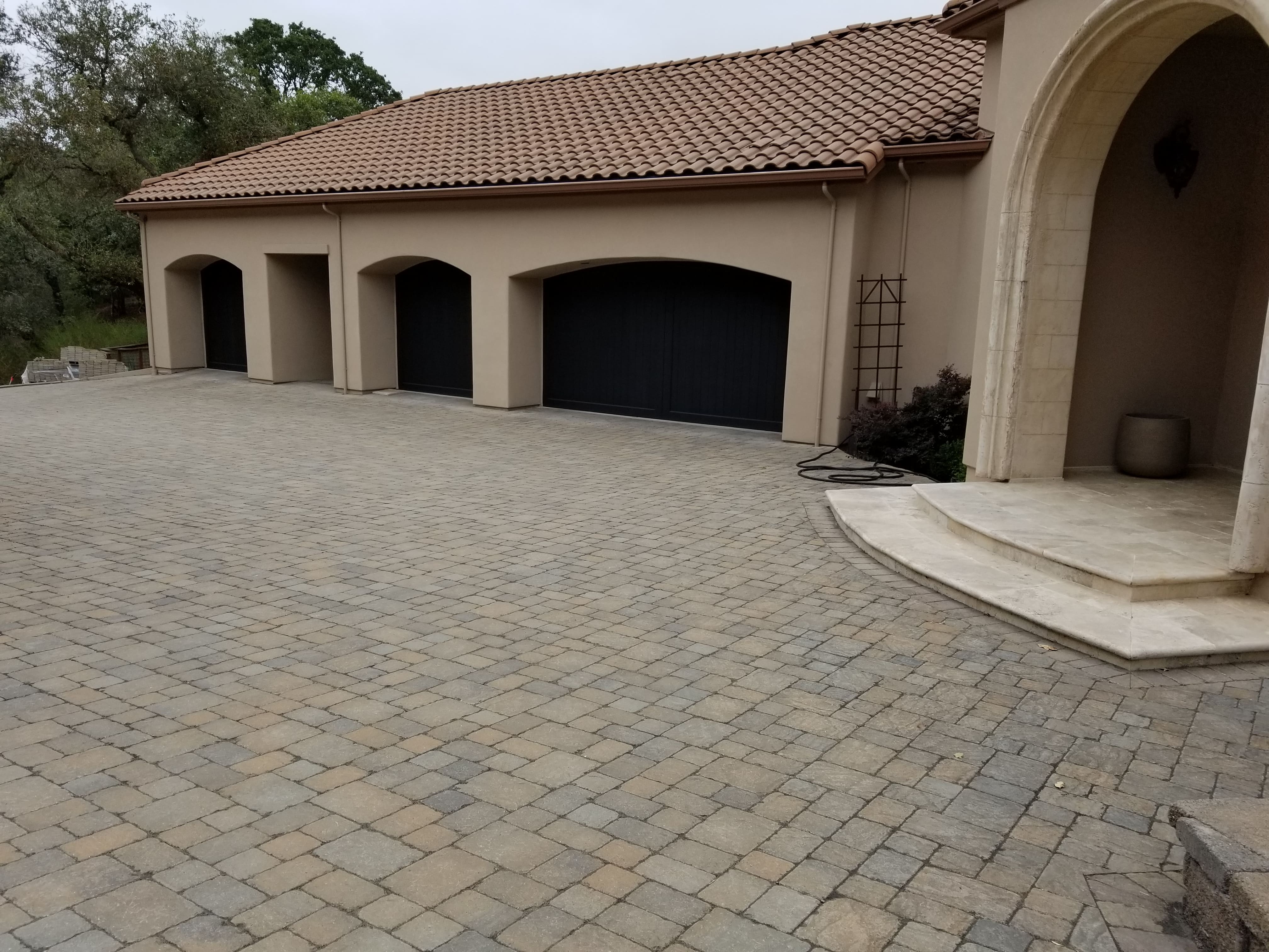 Tumbled paver driveway with cast stone columns and arched garage doors - masonry materials supplied by Paradise Building Materials