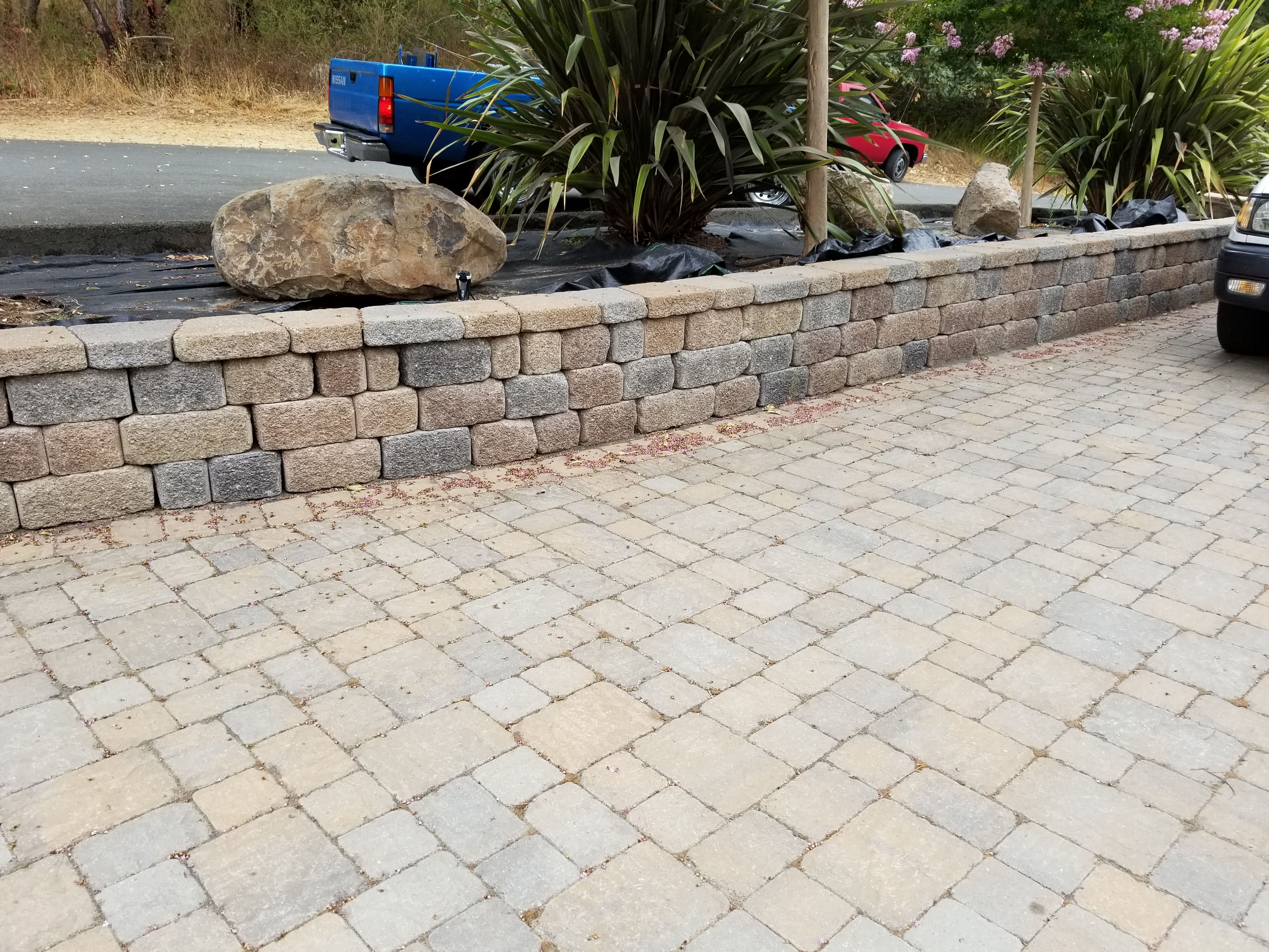 Segmental retaining wall with large boulder accent and paver patio - Paradise Building Materials project