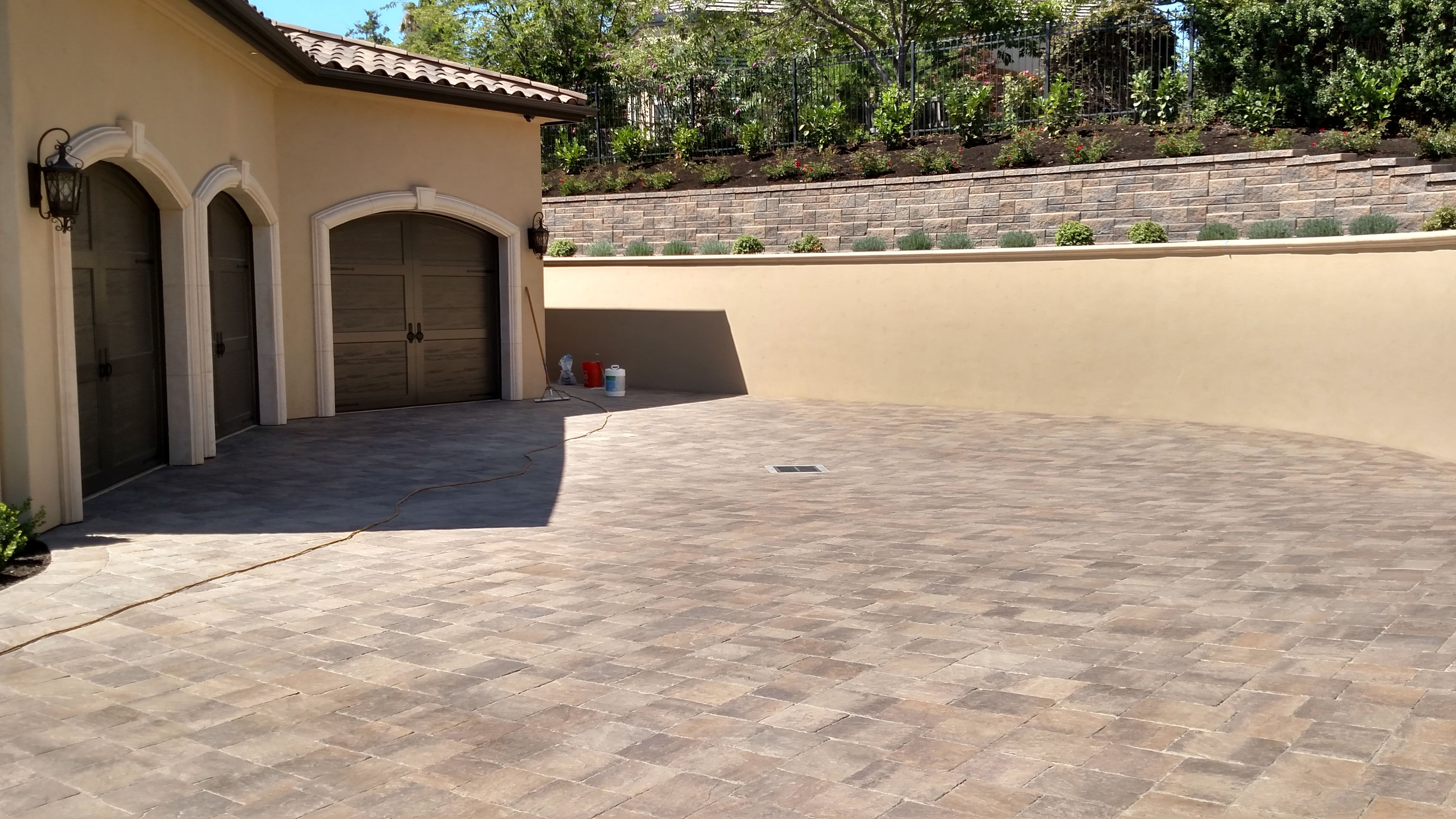 Multi-tiered retaining wall with paver driveway and stucco home - landscape materials from Paradise Building Materials