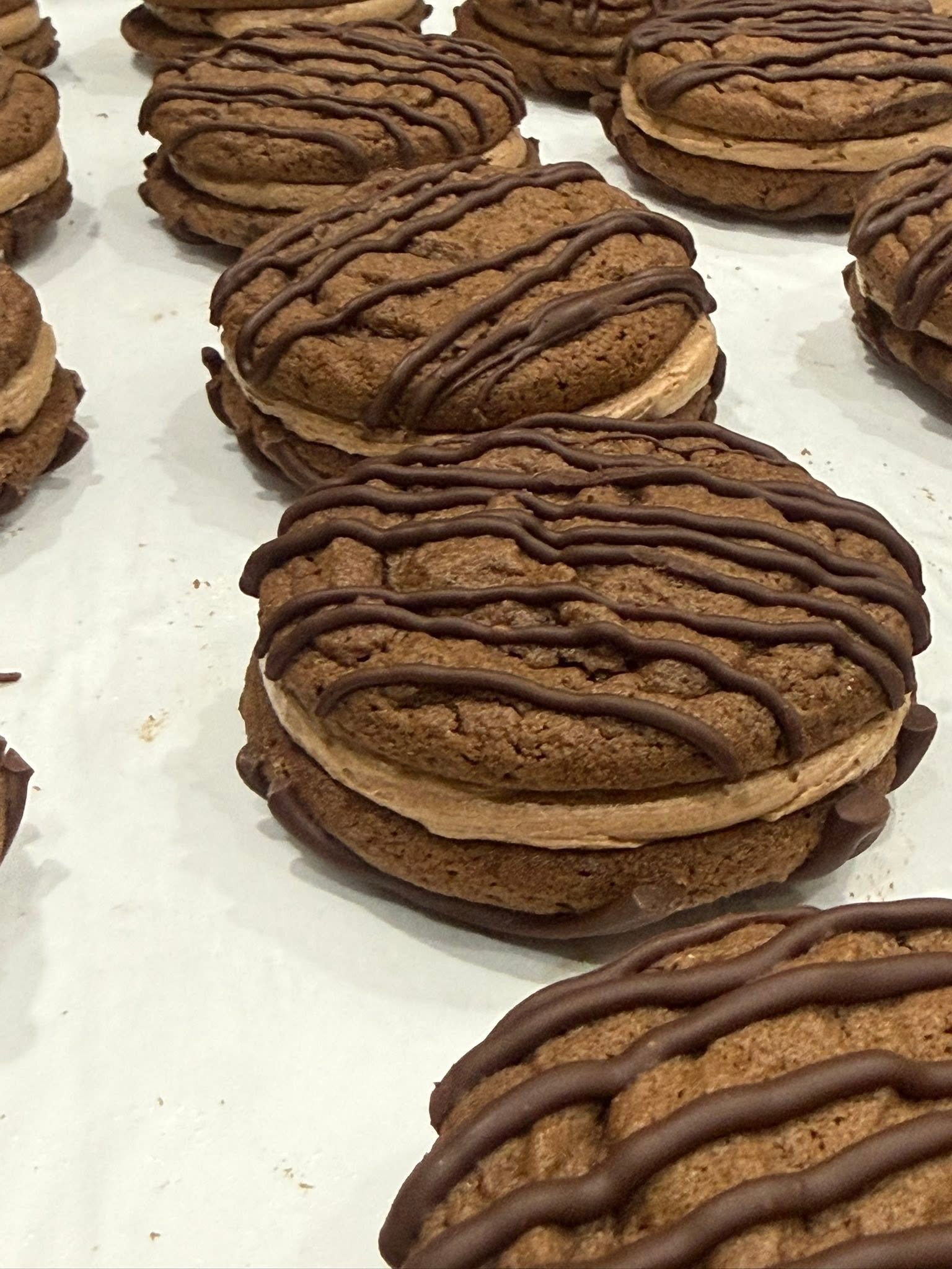 Chocolate sandwich cookies with creamy filling and decorative chocolate drizzle from Sweet Tooth Creations Anchorage bakery