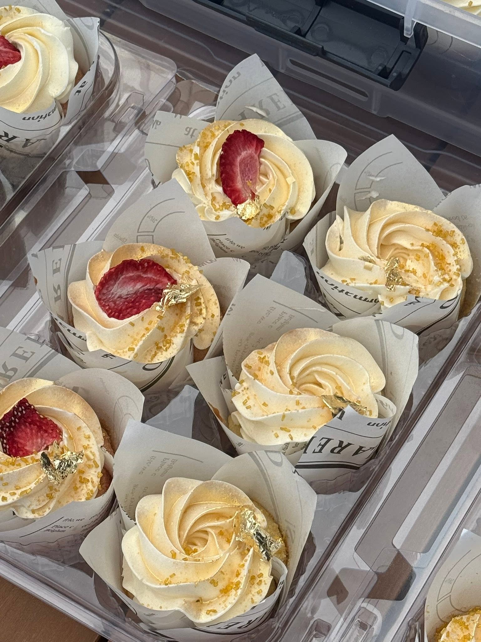 Elegant cupcakes with vanilla buttercream swirls fresh strawberry slices and gold leaf accents from Sweet Tooth Creations