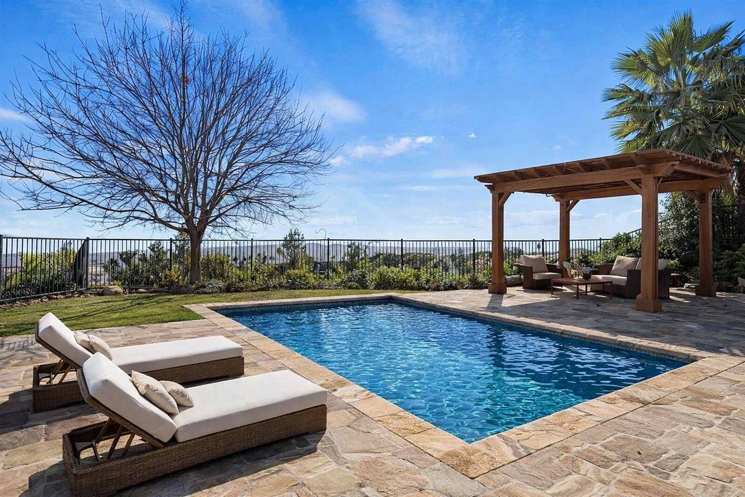 Luxury rectangular pool with stone deck and pergola seating area