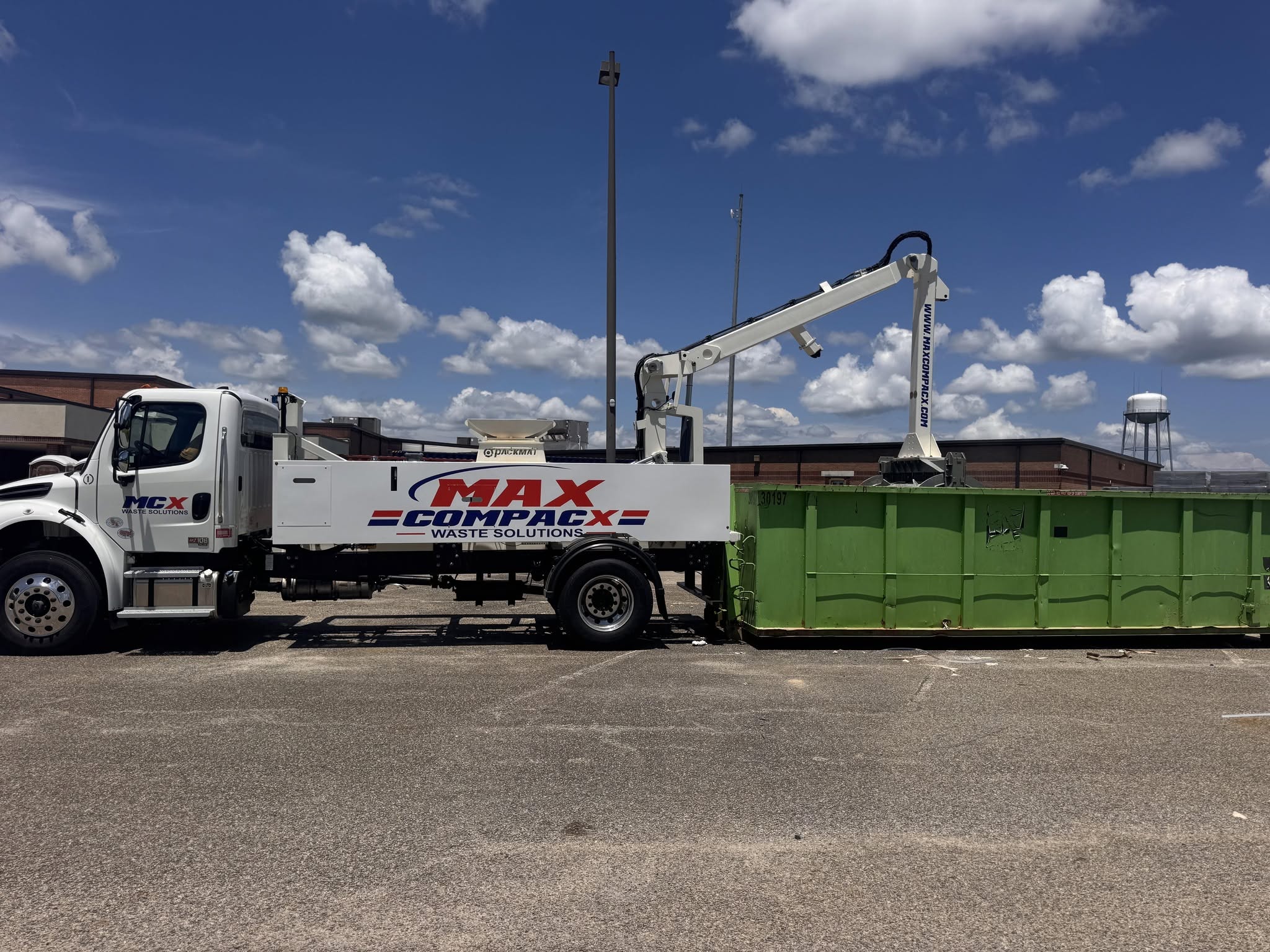 Max Compacx compaction truck working on a roll-off container