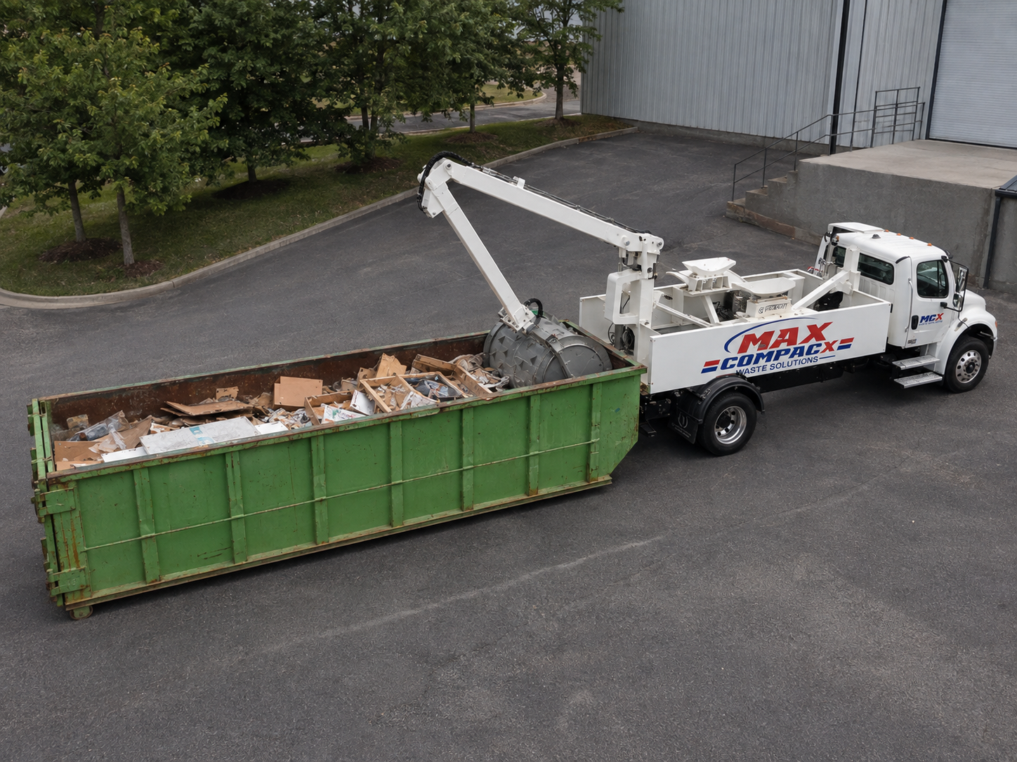 Max Compacx mobile compaction truck pressing waste down inside a roll-off container