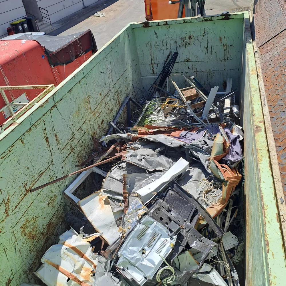 A green roll-off dumpster filled with compacted commercial waste ready for pickup
