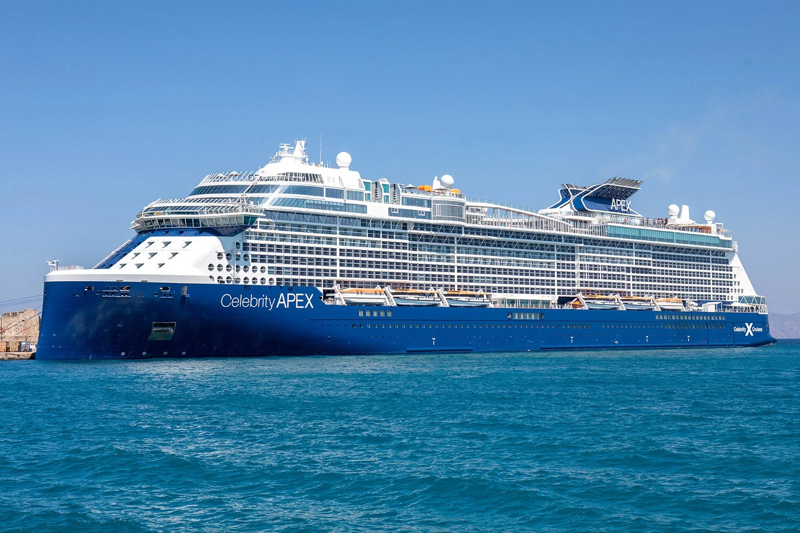 Celebrity Apex modern cruise ship sailing on vibrant turquoise ocean waters under a clear blue sky