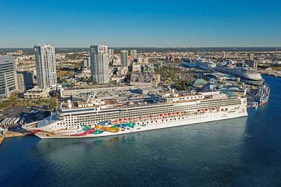 Aerial view of a Norwegian cruise ship docked at Port Tampa Bay with the downtown Tampa skyline in the background