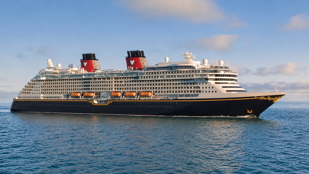 Disney Cruise Line ship sailing across calm ocean waters with iconic red funnels under a clear sky