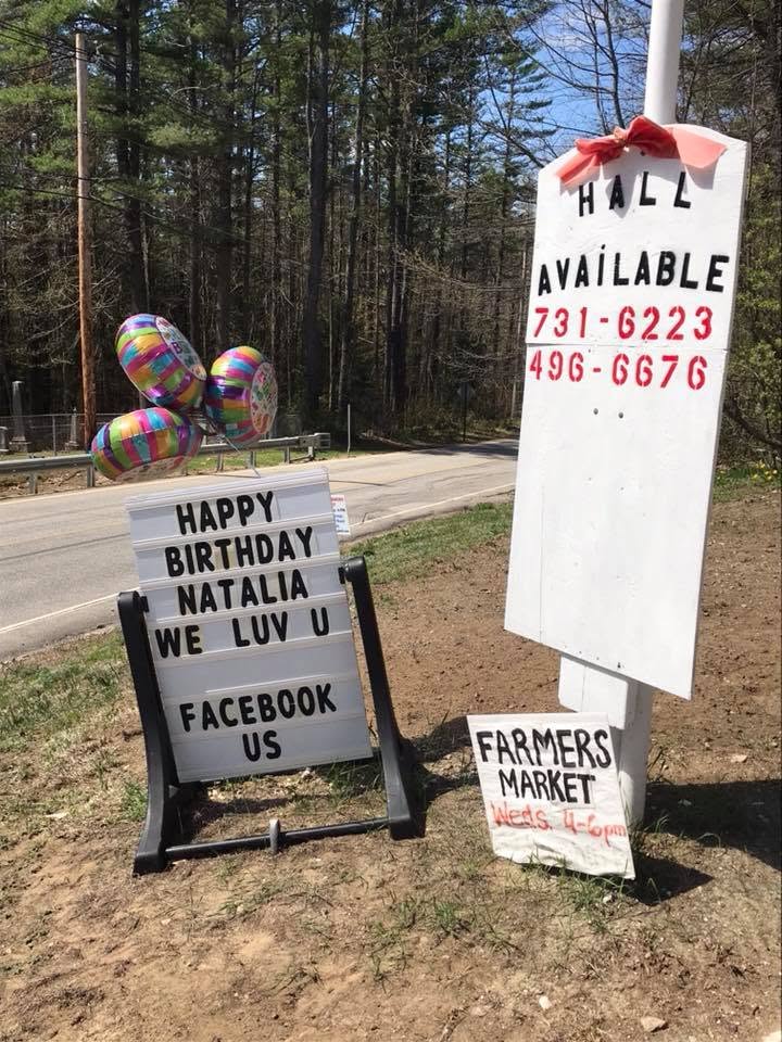 Outdoor sign advertising hall availability and farmers market hours along Horse Hill Road