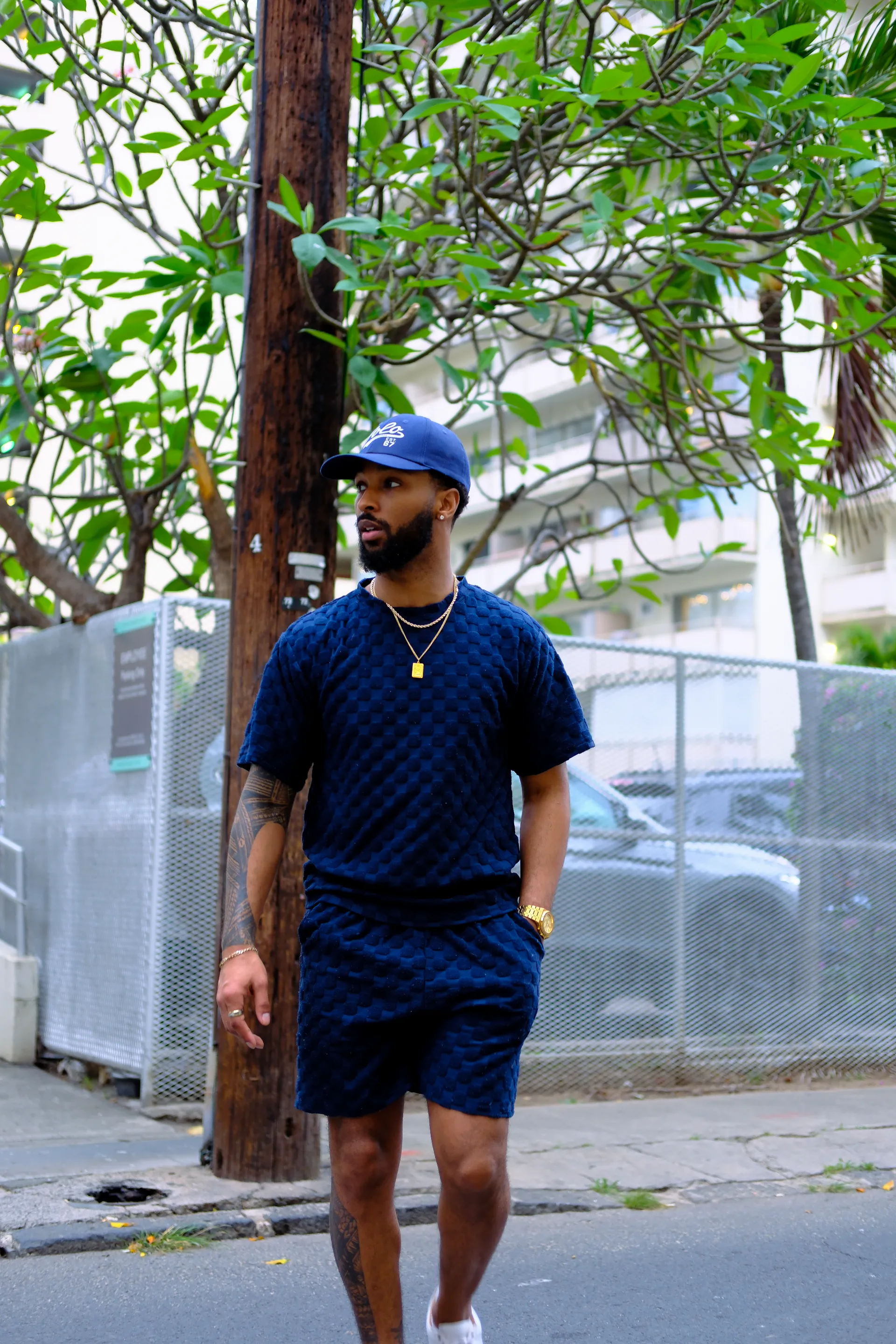 Jai'koa Parham walking in a navy blue textured matching set and cap, street style lifestyle campaign