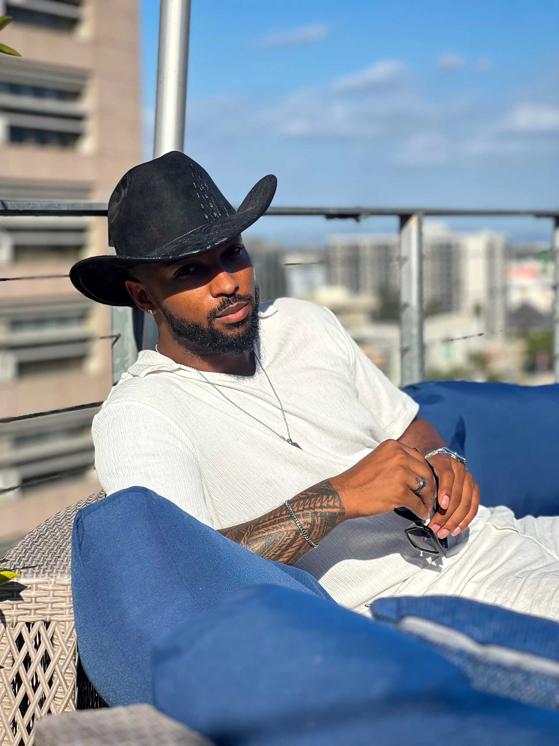 Jai'koa Parham rooftop editorial in a cowboy hat and white ribbed shirt with city view