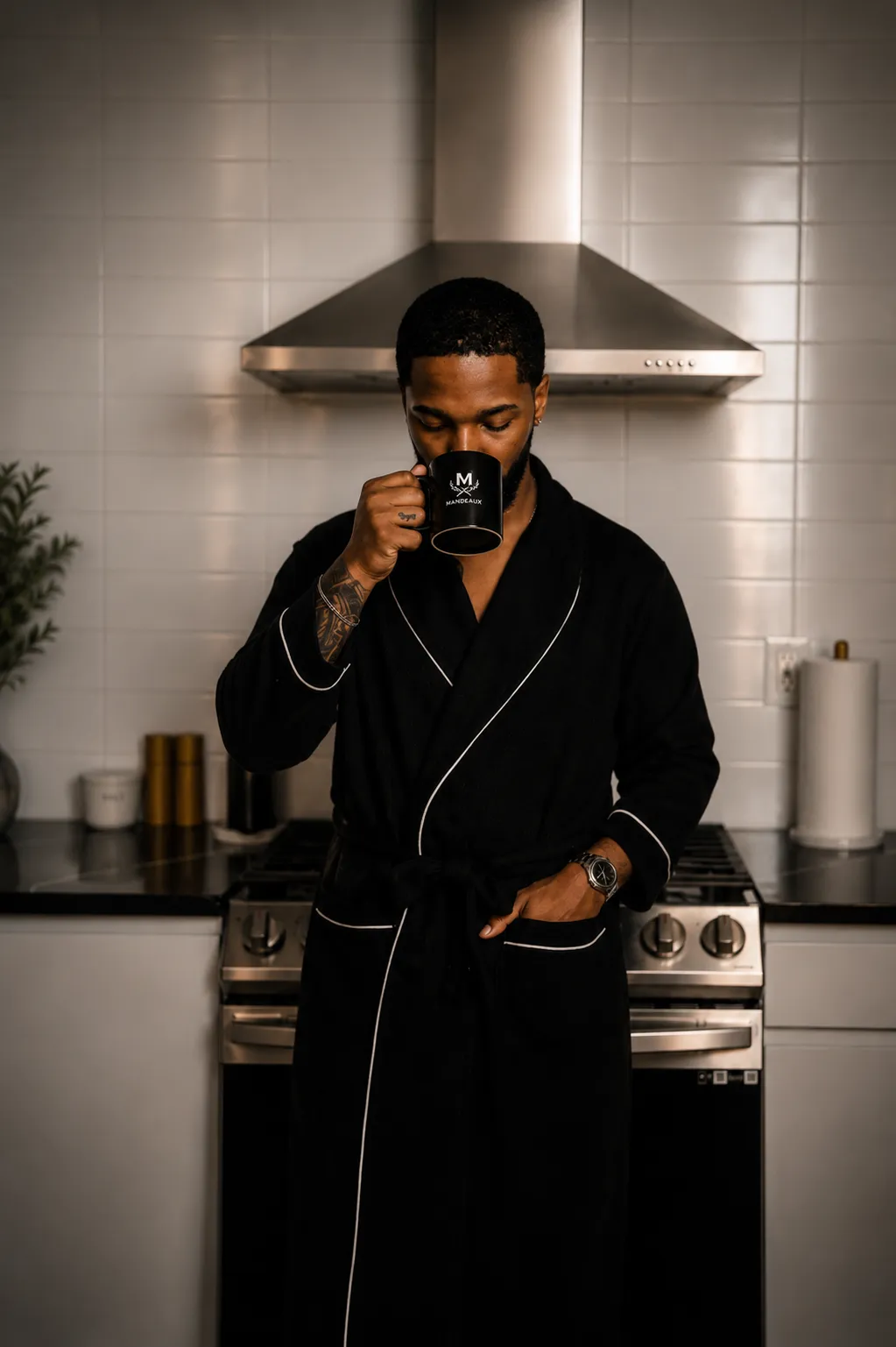 Jai'koa Parham in a luxury black robe holding a Mandeaux coffee mug in a modern kitchen, lifestyle campaign