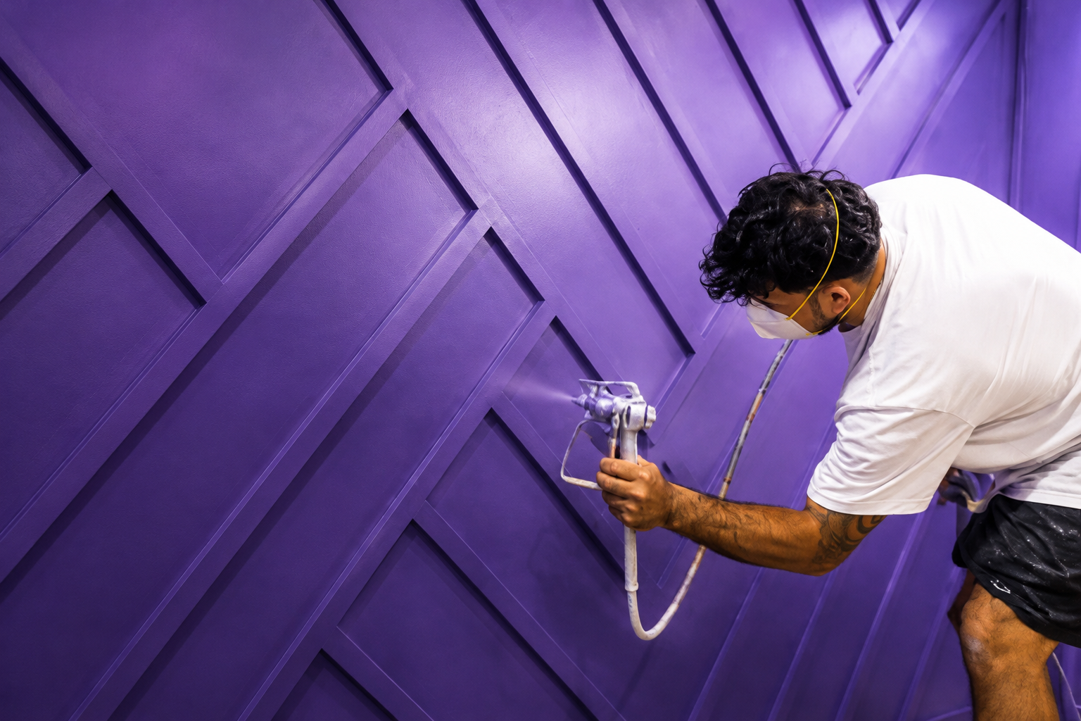 Professional painter spraying purple cabinetry — Rose Painting Group at work