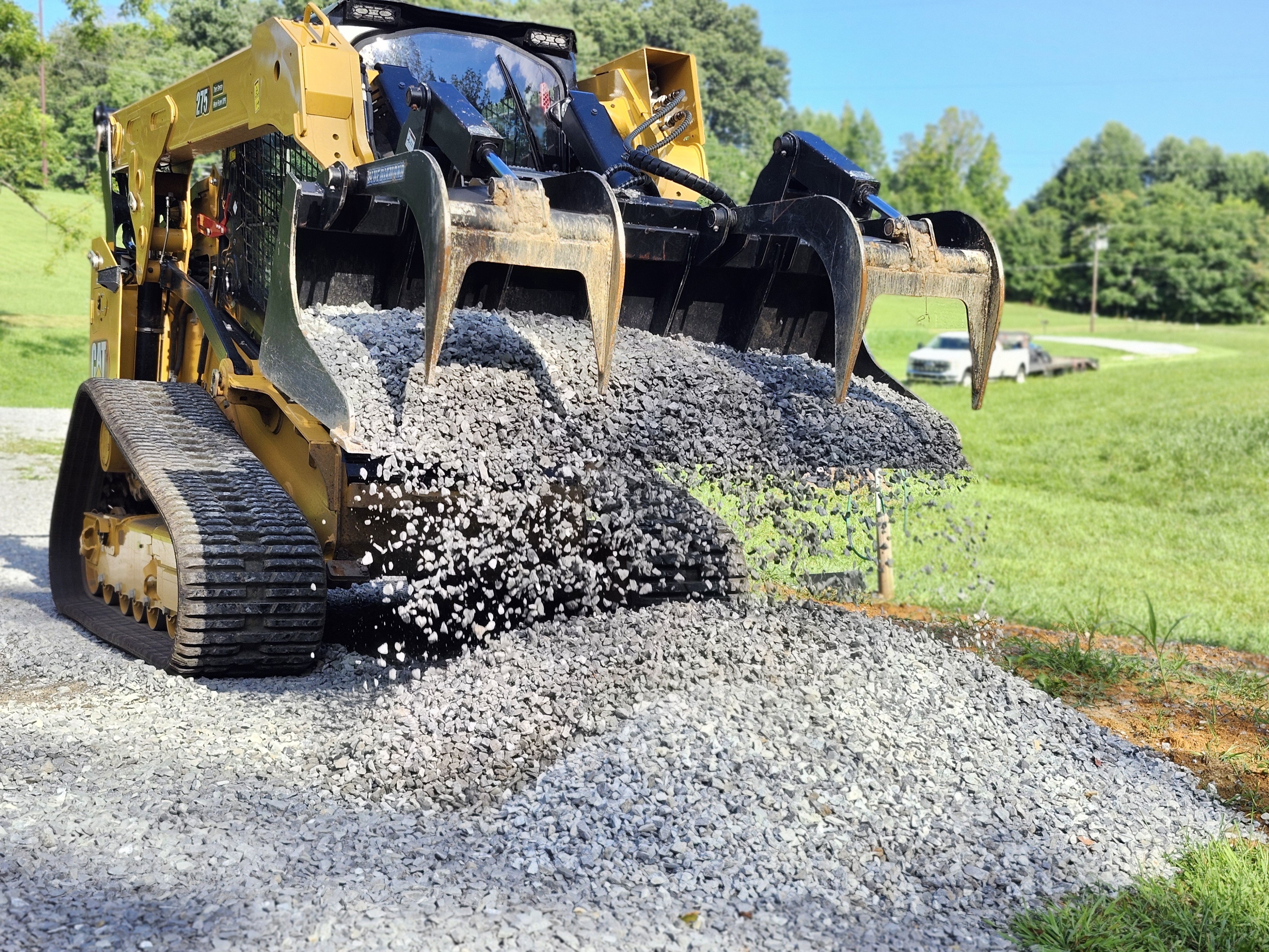 CAT 275 compact track loader with grapple bucket moving crushed stone gravel for driveway repair
