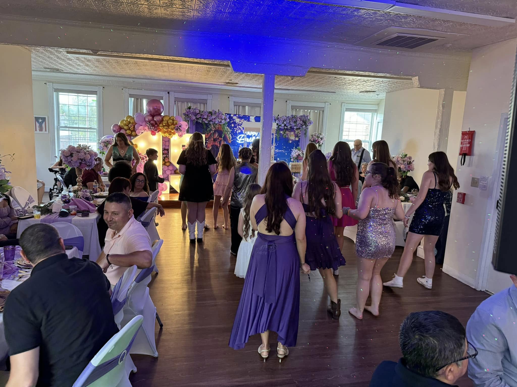 Guests dancing at a quinceañera celebration with balloon arch in Delaware