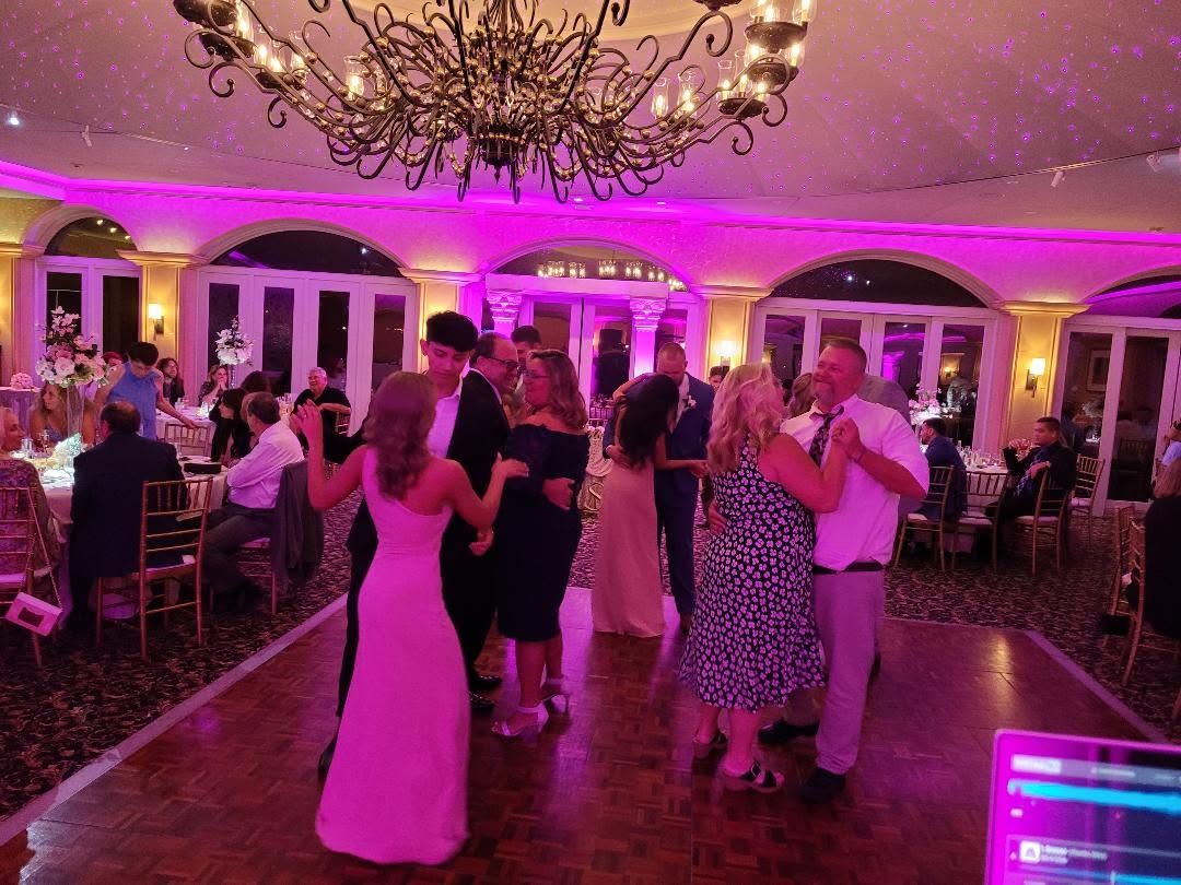 Packed dance floor at a Delaware wedding reception with purple uplighting