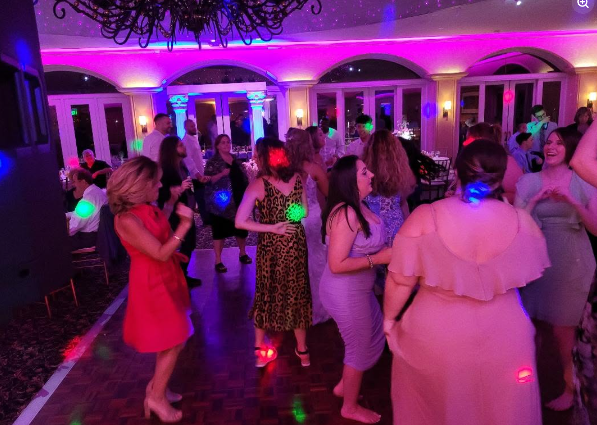 Packed dance floor with pink and purple uplighting at a Delaware reception