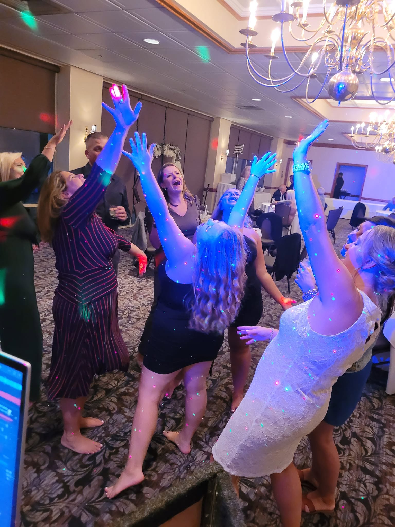 Wedding guests dancing with hands in the air under blue lighting at a Delaware reception