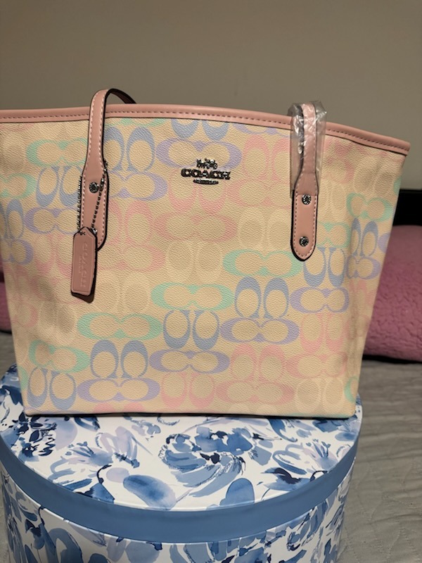 Beige cream Coach signature monogram tote bag with pastel rainbow logo pattern in pink blue green lavender dual top handles with protective wrapping displayed on floral box