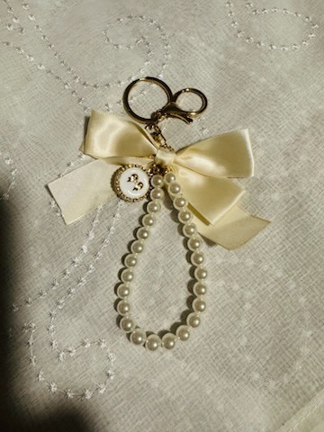 Cream silk bow keychain charm with pearl beaded wristlet strap and gold hardware accents
