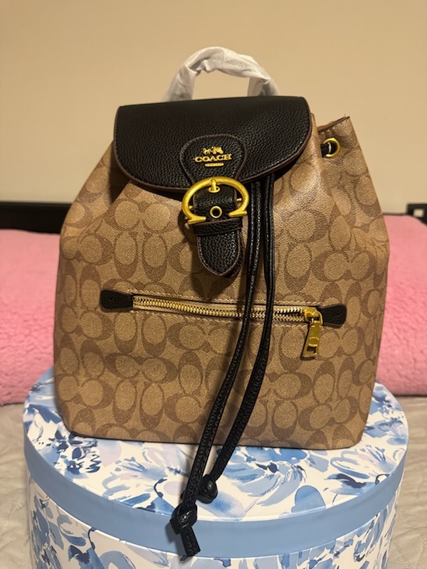 Beige tan Coach signature monogram backpack with black leather top panel gold horse carriage logo buckle drawstring closure front zip pocket on floral display box