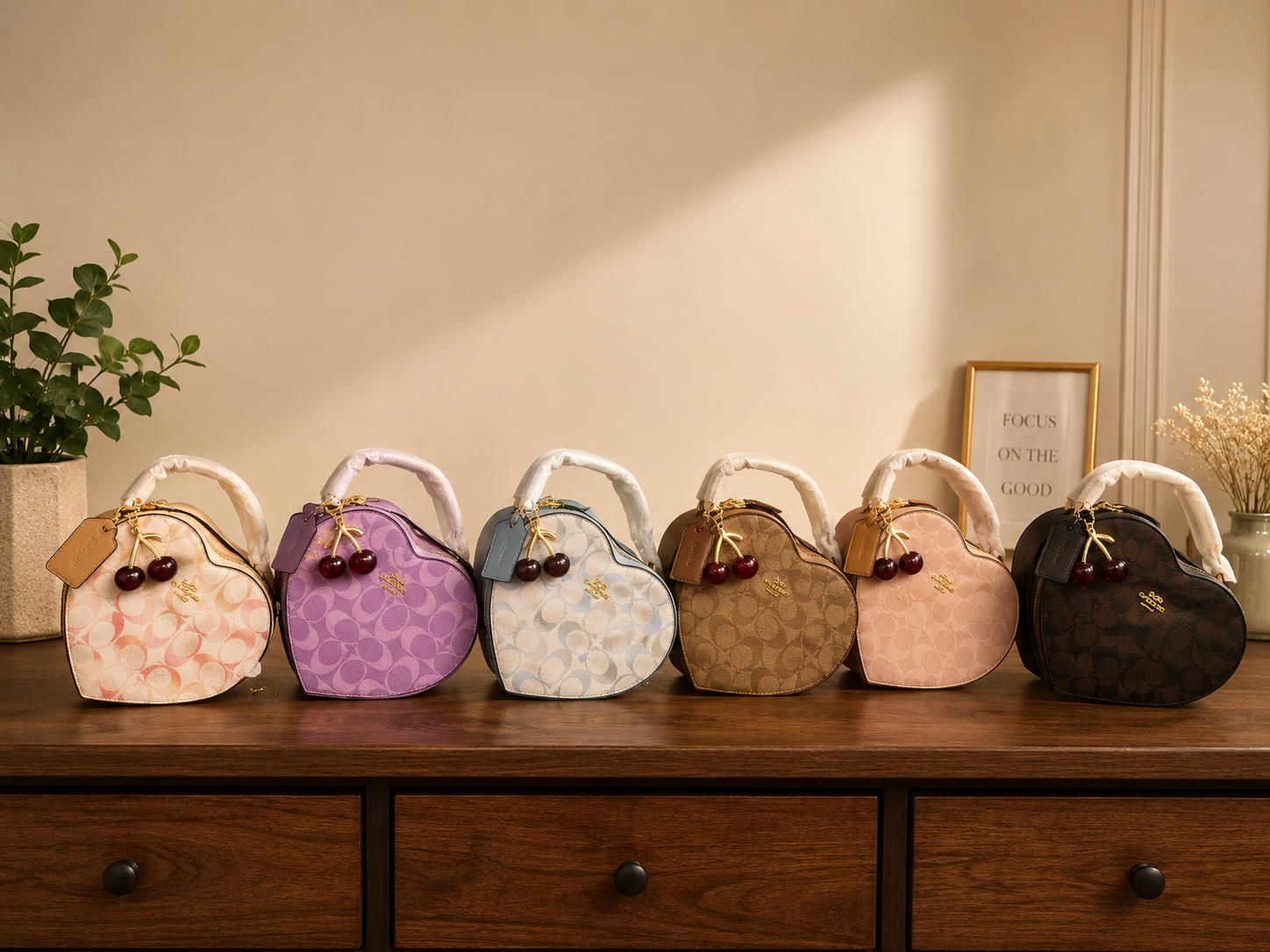 Coach heart-shaped bag color collection displaying seven designer bags in beige purple blue brown pink black colors with cherry charm keychains on wooden surface